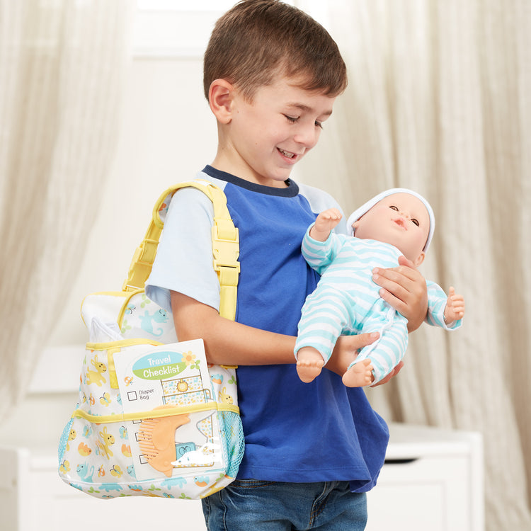 A kid playing with The Melissa & Doug Mine to Love Travel Time Play Set for Dolls with Diaper Bag, Bottle, Sunscreen, More (17 pcs)