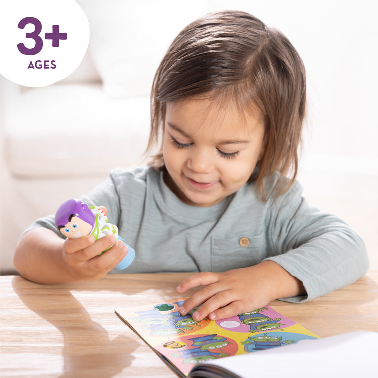 A kid playing with The Melissa & Doug Sticker Wow!™ Disney Buzz Lightyear Bundle: 24-Page Activity Book, Refillable Sticker Stamper, Mini Pad, 500 Stickers, Arts and Crafts for Kids Ages 3+