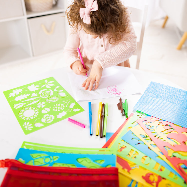 A kid playing with The Melissa & Doug Created by Me! Stencil Art Coloring Activity Kit in Storage Pouch -- 170+ Designs, 6 Markers, 2 Crayons, Paper