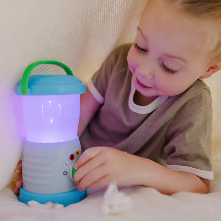 A kid playing with The Melissa & Doug Let’s Explore™ Light & Sound Camping Lantern Play Set