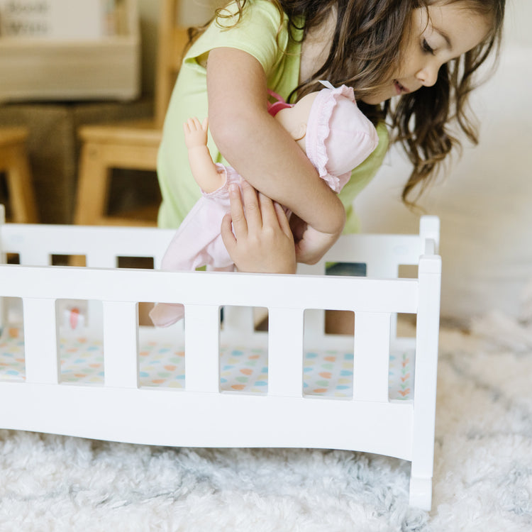 A kid playing with The Melissa & Doug Mine to Love Wooden Play Cradle for Dolls, Stuffed Animals - White