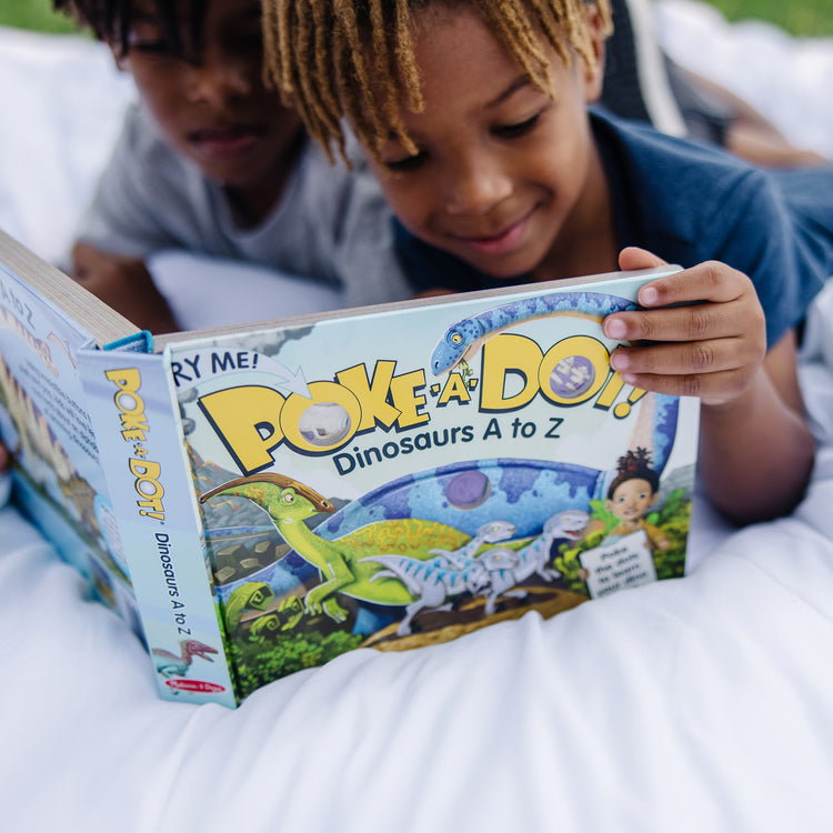 A kid playing with The Melissa & Doug Children's Book - Poke-A-Dot: Dinosaurs A to Z (Board Book with Buttons to Pop)