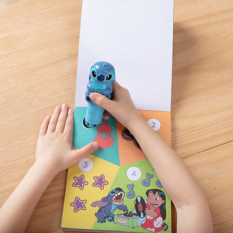A kid playing with The Melissa & Doug Sticker WOW! Disney Stitch 24-Page Activity Pad with 300 Stickers - For Ages 3+