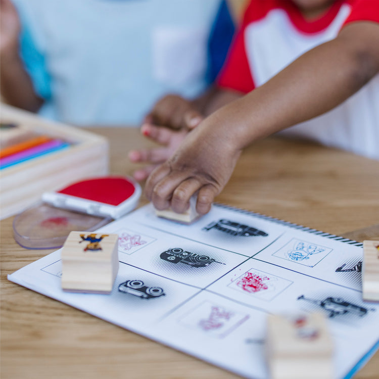 A kid playing with The Melissa & Doug PAW Patrol Wooden Stamps Activity Set With Markers, Activity Pad (25 Pieces)