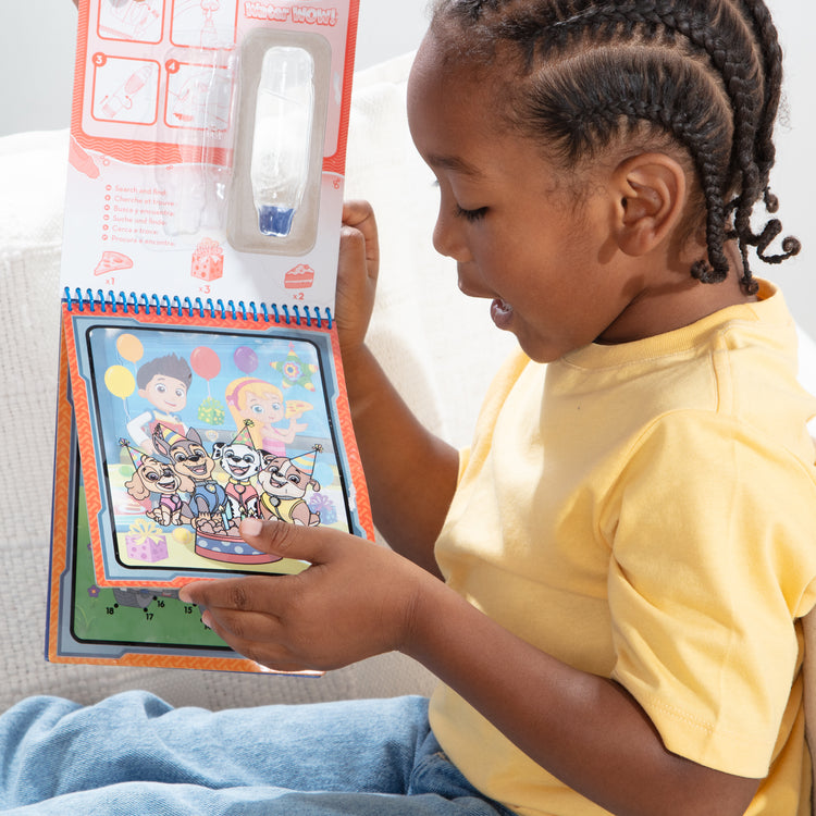 A kid playing with The Melissa & Doug Water WOW! PAW Patrol Chase Reusable Coloring Book with Refillable Water Pen - For Ages 3+