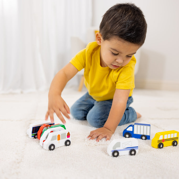 A kid playing with The Melissa & Doug Wooden Town Vehicles Set in Wooden Tray (9 pcs)