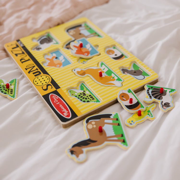 A kid playing with The Melissa & Doug Pets Sound Puzzle - Wooden Peg Puzzle With Sound Effects (8 pcs)