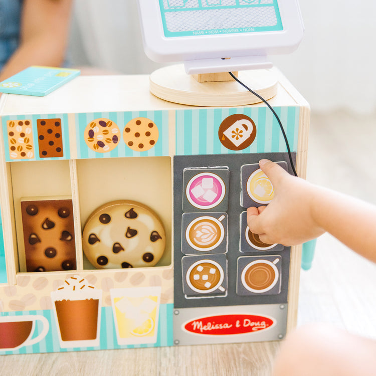 A kid playing with The Melissa & Doug Wooden Café Barista Coffee Shop (35 Pieces)