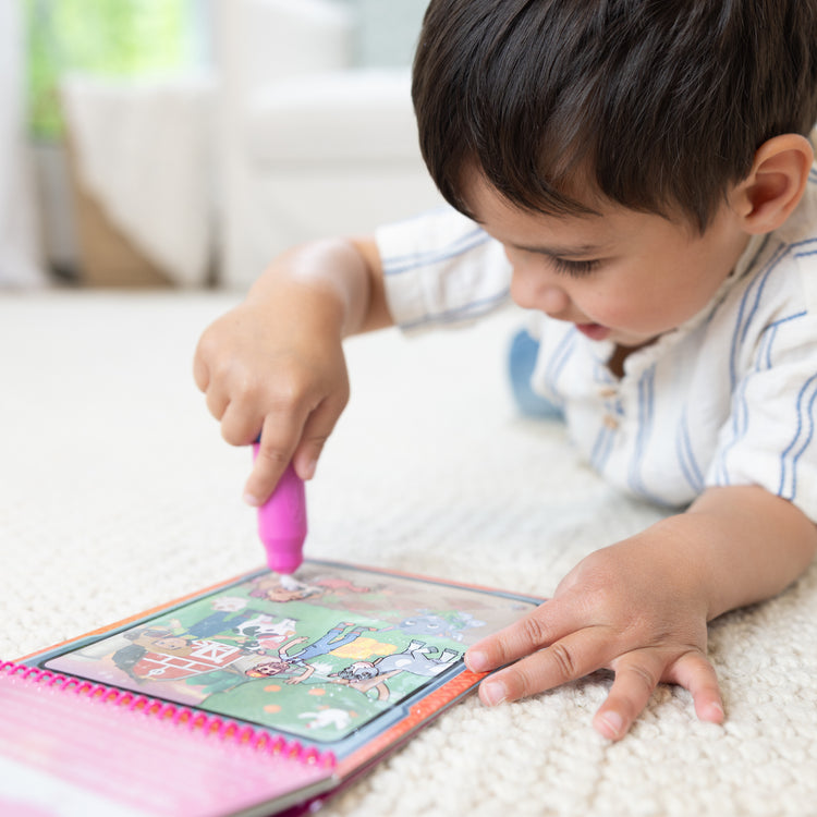 A kid playing with The Melissa & Doug Water WOW! PAW Patrol Skye Reusable Coloring Book with Refillable Water Pen - For Ages 3+
