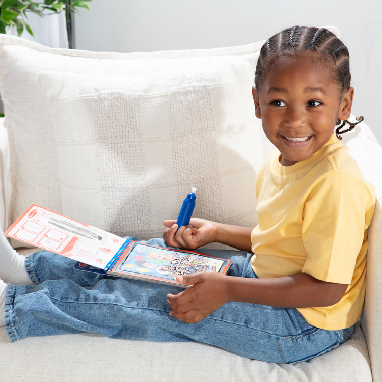 A kid playing with The Melissa & Doug Water WOW! PAW Patrol Chase Reusable Coloring Book with Refillable Water Pen - For Ages 3+