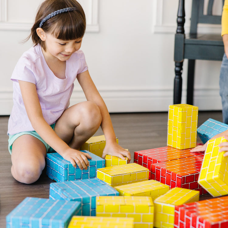A kid playing with The Melissa & Doug Extra-Thick Cardboard Building Blocks - 24 Blocks in 3 Sizes