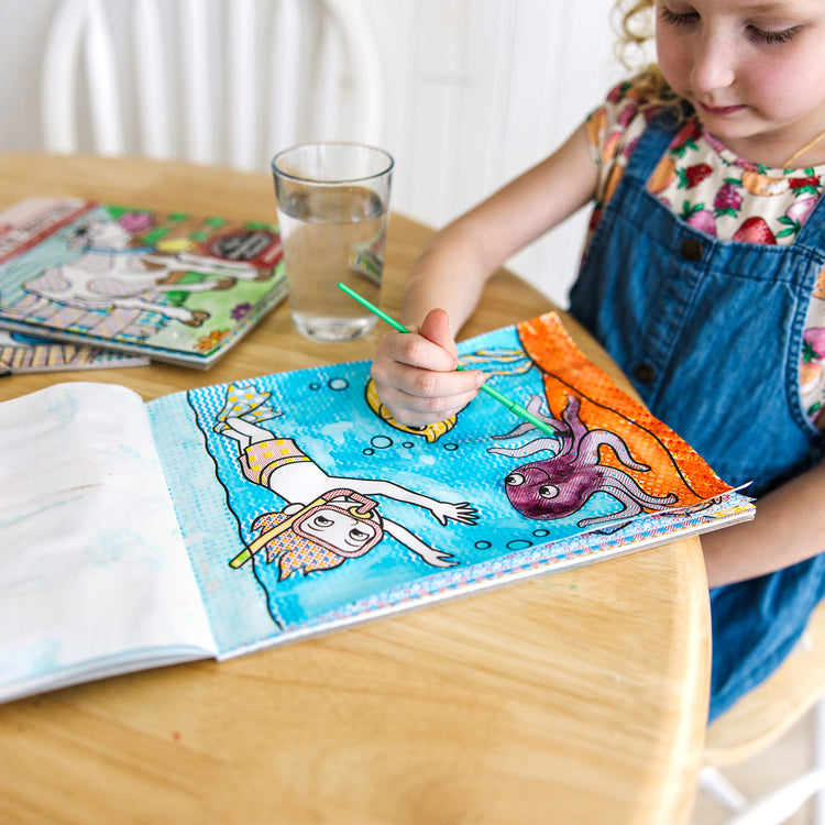 A kid playing with The Melissa & Doug My First Paint With Water Activity Books Set - Animals, Vehicles, and Pirates