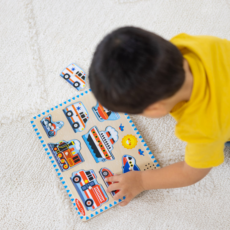 A kid playing with The Melissa & Doug Wooden Sound Puzzle 2-Pack for Toddler and Preschool Boys and Girls – Farm Animals, Vehicles