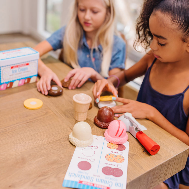 A kid playing with The Melissa & Doug Scoops and Sandwiches 13-Piece Ice Cream Play Food Set