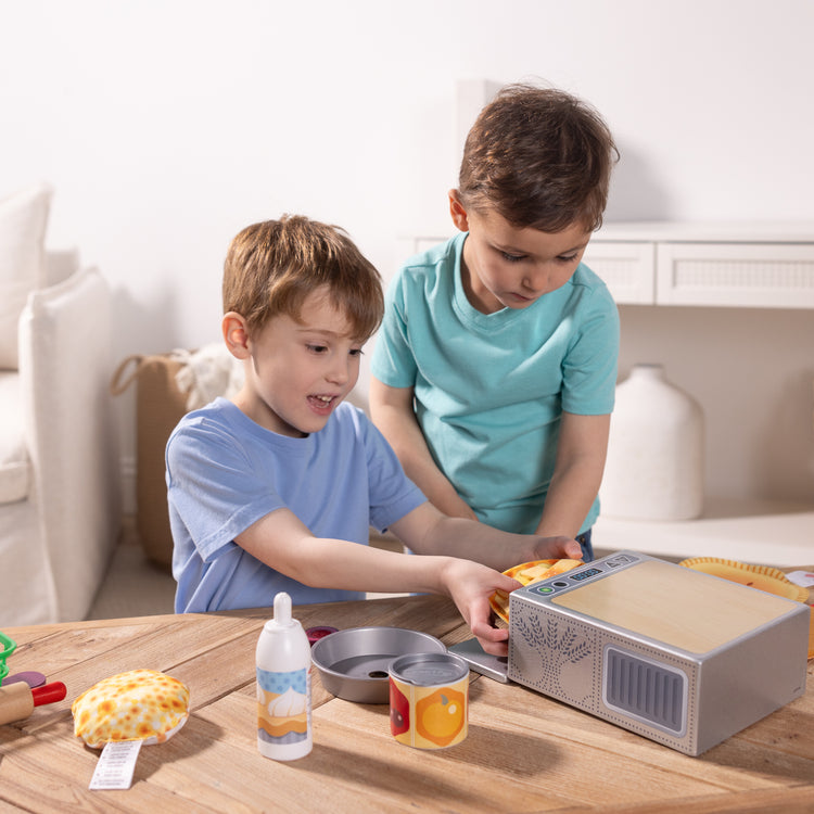 A kid playing with The Melissa & Doug Make and Bake Pies Pretend Play Food Set And Wooden Oven With Squishy Dough for Ages 3+