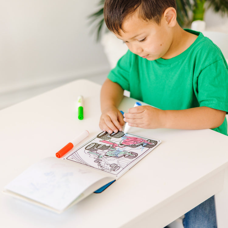 A kid playing with The Melissa & Doug On the Go Magicolor Coloring Pad: Adventure - 18 Coloring Pages and 4 Markers
