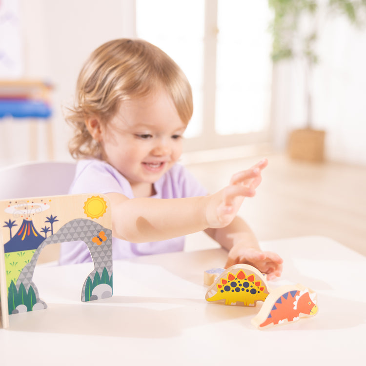 A kid playing with The Wooden Dinosaurs Play Set