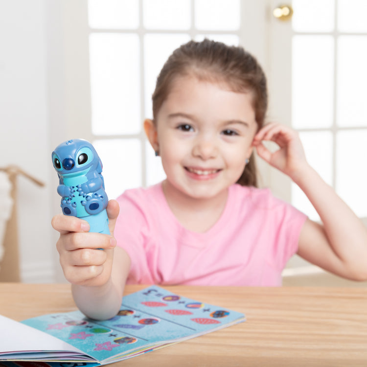 A kid playing with The Melissa & Doug Sticker WOW! Disney Stitch Bundle with 2 Activity Pads and 500 Stickers - For Ages 3+