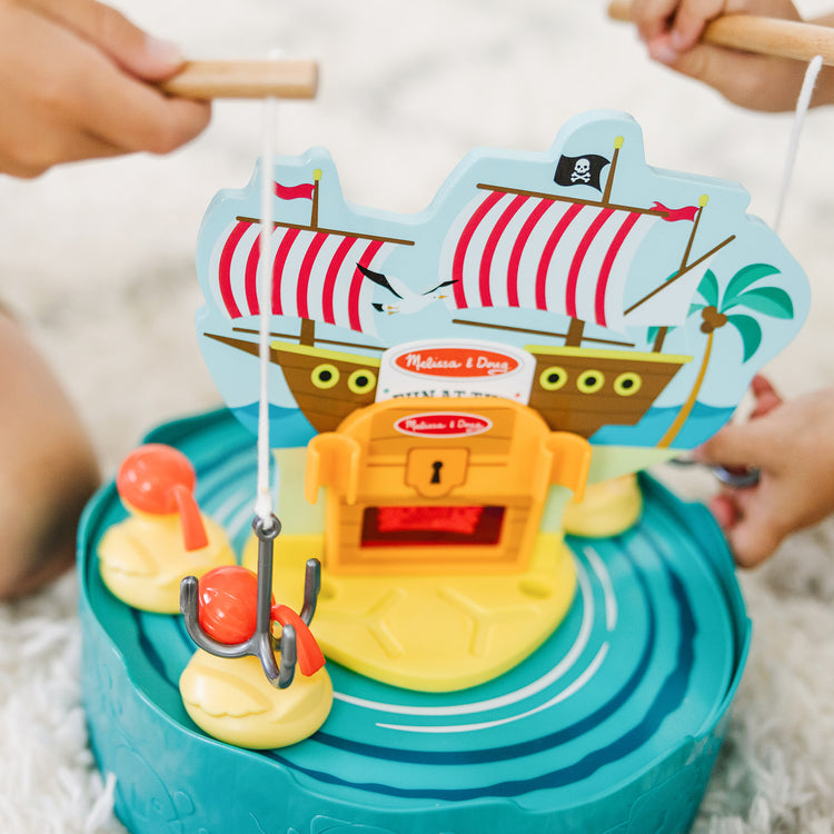 A kid playing with The Melissa & Doug Fun at the Fair! Hook a Duck Pirate Fishing Game