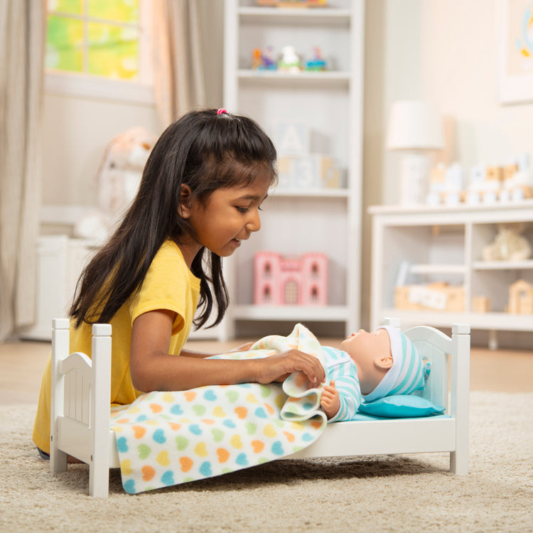 A kid playing with The Melissa & Doug Mine to Love Wooden Play Bed for Dolls, Stuffed Animals - White (8.7”H x 9.1”W x 20.7”L Assembled)
