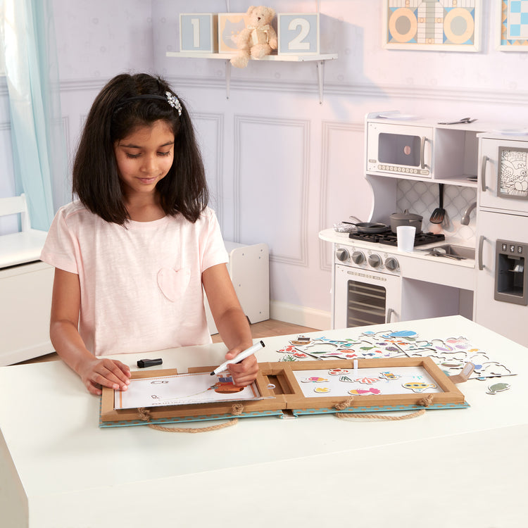 A kid playing with The Melissa & Doug Natural Play: Play, Draw, Create Reusable Drawing & Magnet Kit – Ocean (42 Magnets, 5 Dry-Erase Markers)