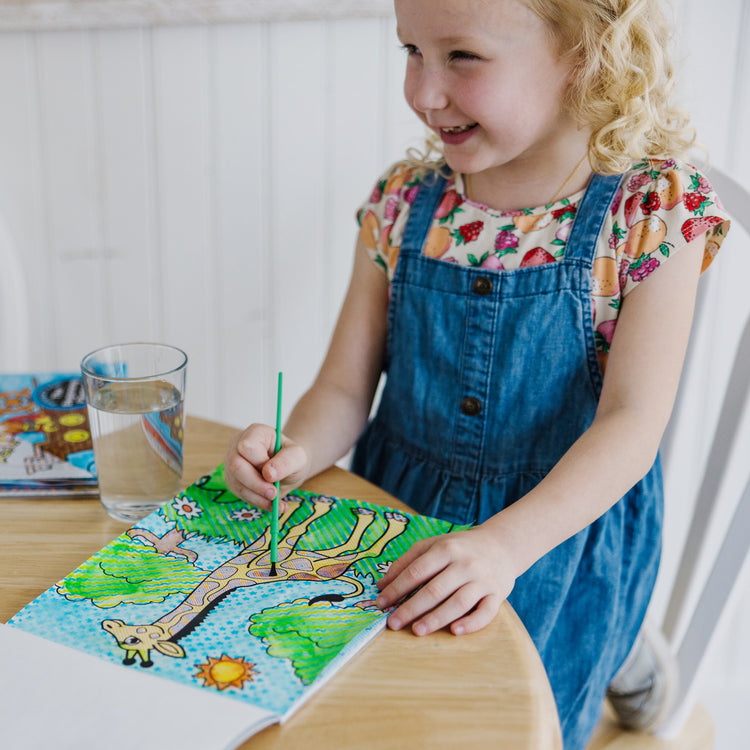 A kid playing with The Melissa & Doug My First Paint With Water Activity Books Set - Animals, Vehicles, and Pirates