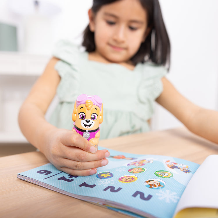 A kid playing with The Melissa & Doug Sticker WOW!™ PAW Patrol Skye Bundle: 24-Page Activity Pad, Sticker Stamper, 500 Stickers, Mini Pad, Arts and Crafts Fidget Toy Collectible Character