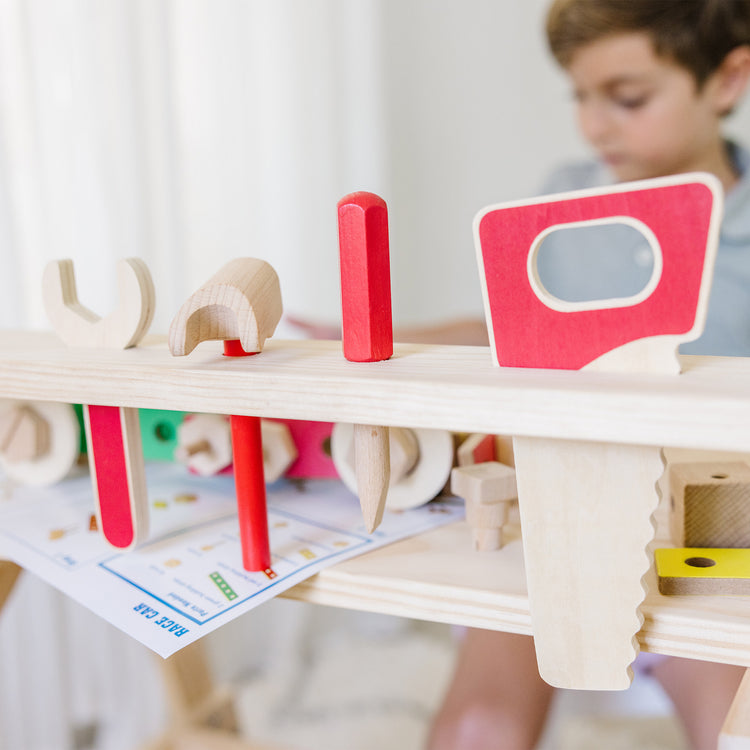 A kid playing with The Melissa & Doug Solid Wood Project Workbench Play Building Set