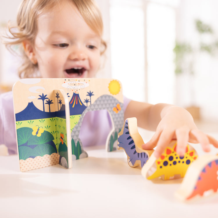 A kid playing with The Wooden Dinosaurs Play Set