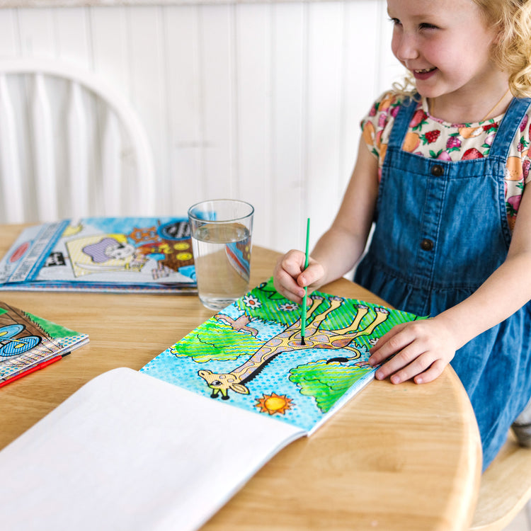 A kid playing with The Melissa & Doug My First Paint With Water Activity Books Set - Animals, Vehicles, and Pirates