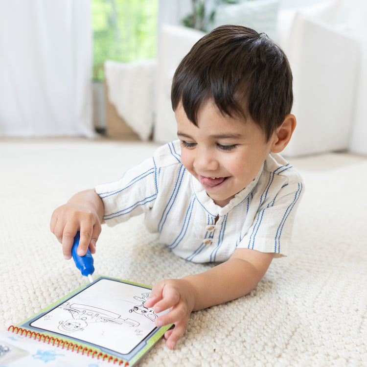A kid playing with The Melissa & Doug Water WOW! PAW Patrol Marshall Reusable Coloring Book with Refillable Water Pen - For Ages 3+