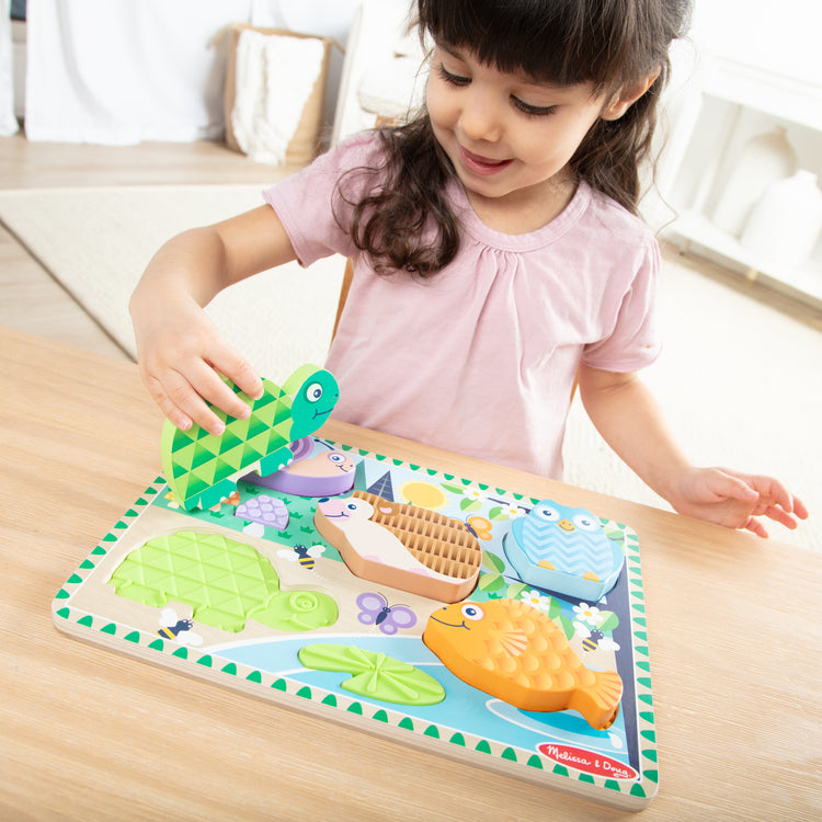 A kid playing with The Melissa & Doug Forest Friends Touch & Feel Wooden Puzzle, 5-Piece Chunky Toddler Puzzles with Animals & Textured Silicone Puzzle Board Inlays, Preschool Toys for Girls & Boys Ages 2 and Up