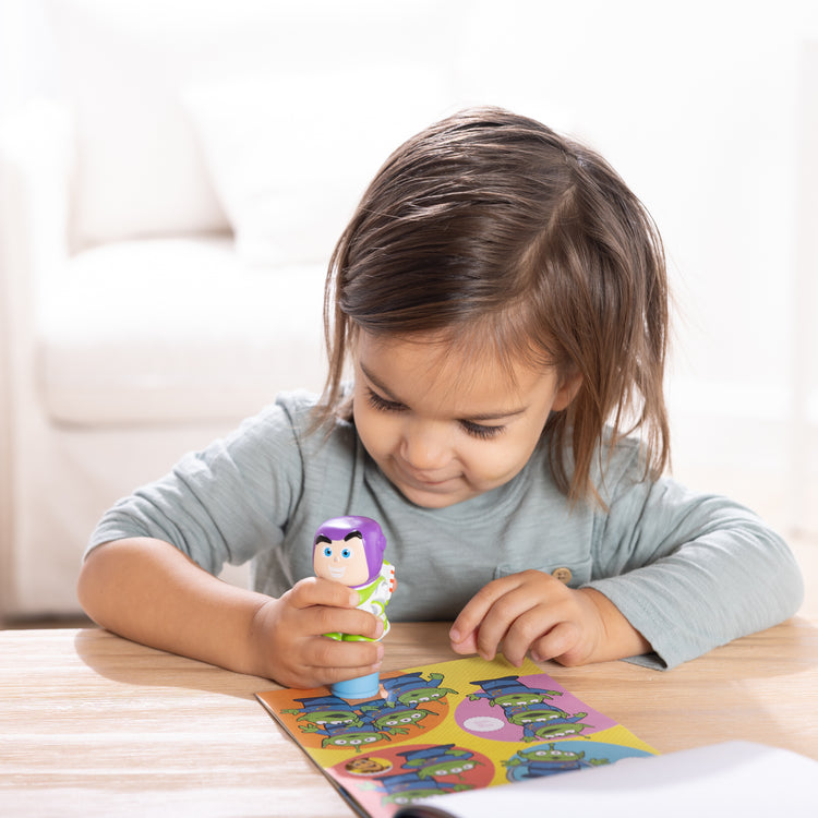 A kid playing with The Melissa & Doug Sticker Wow!™ Disney Buzz Lightyear Bundle: 24-Page Activity Book, Refillable Sticker Stamper, Mini Pad, 500 Stickers, Arts and Crafts for Kids Ages 3+