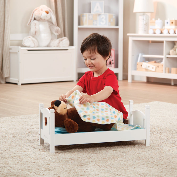 A kid playing with The Melissa & Doug Mine to Love Wooden Play Bed for Dolls, Stuffed Animals - White (8.7”H x 9.1”W x 20.7”L Assembled)