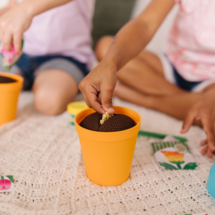A kid playing with The Melissa & Doug Let’s Explore Flower Gardening Play Set with Color-Changing Flowers (16 Pieces)