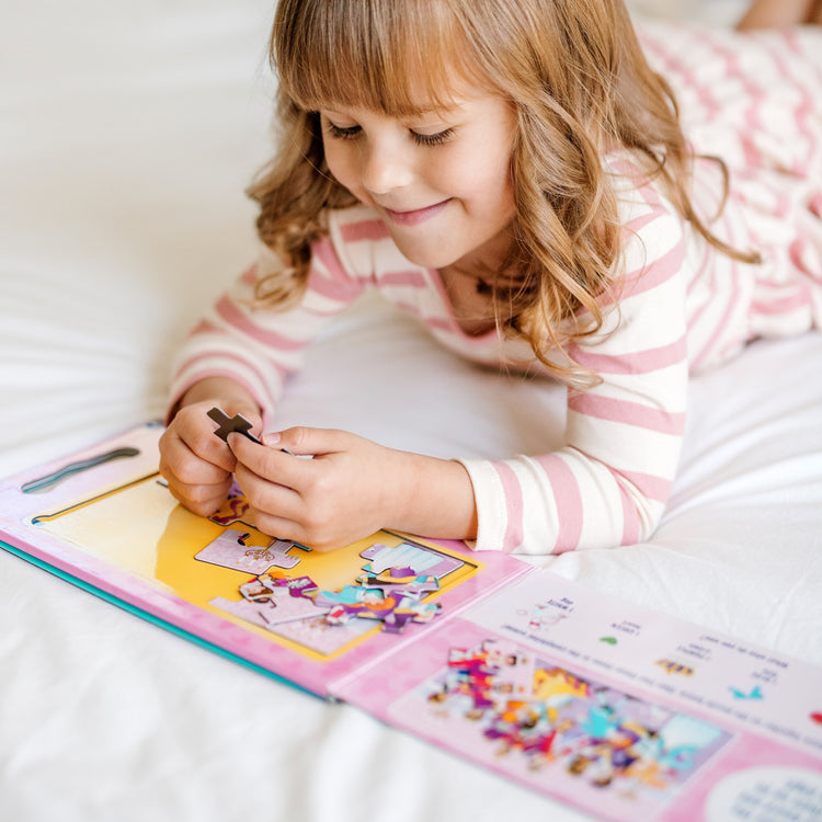 A kid playing with The Melissa & Doug Take-Along Magnetic Jigsaw Puzzles Travel Toy – Princesses (2 15-Piece Puzzles)