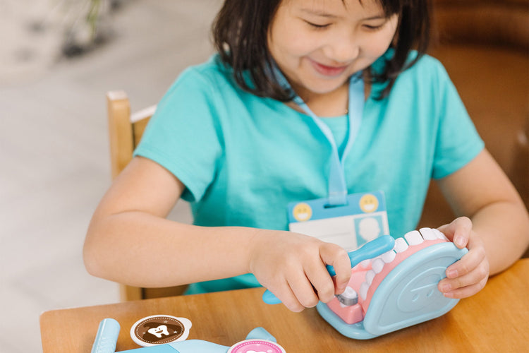 A kid playing with The Melissa & Doug Super Smile Dentist Kit With Pretend Play Set of Teeth And Dental Accessories (25 Toy Pieces)