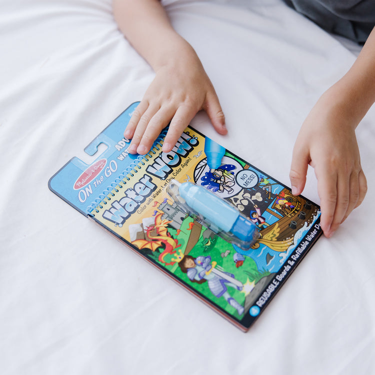 A kid playing with The Melissa & Doug On the Go Water Wow! Reusable Water-Reveal Activity Pad Travel Toy – Adventure