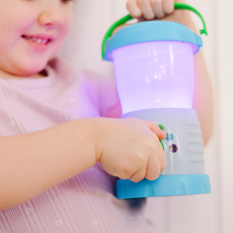 A kid playing with The Melissa & Doug Let’s Explore™ Light & Sound Camping Lantern Play Set