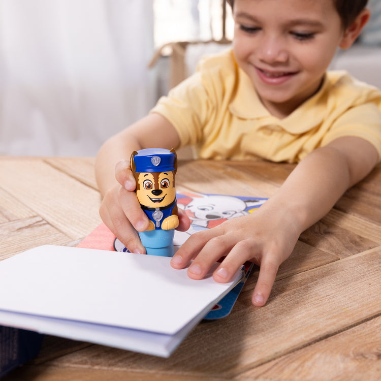 A kid playing with The Melissa & Doug Sticker WOW!™ 24-Page Activity Pad and Sticker Stamper, 300 Stickers, Arts and Crafts Fidget Toy Collectible Character – PAW Patrol Chase
