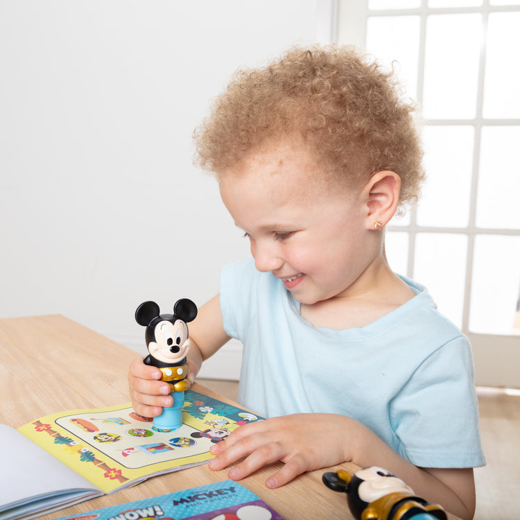 A kid playing with The Melissa & Doug Sticker WOW! Disney Special Edition Pack with Mickey & Minnie Stampers and 900 Stickers - Ages 3+