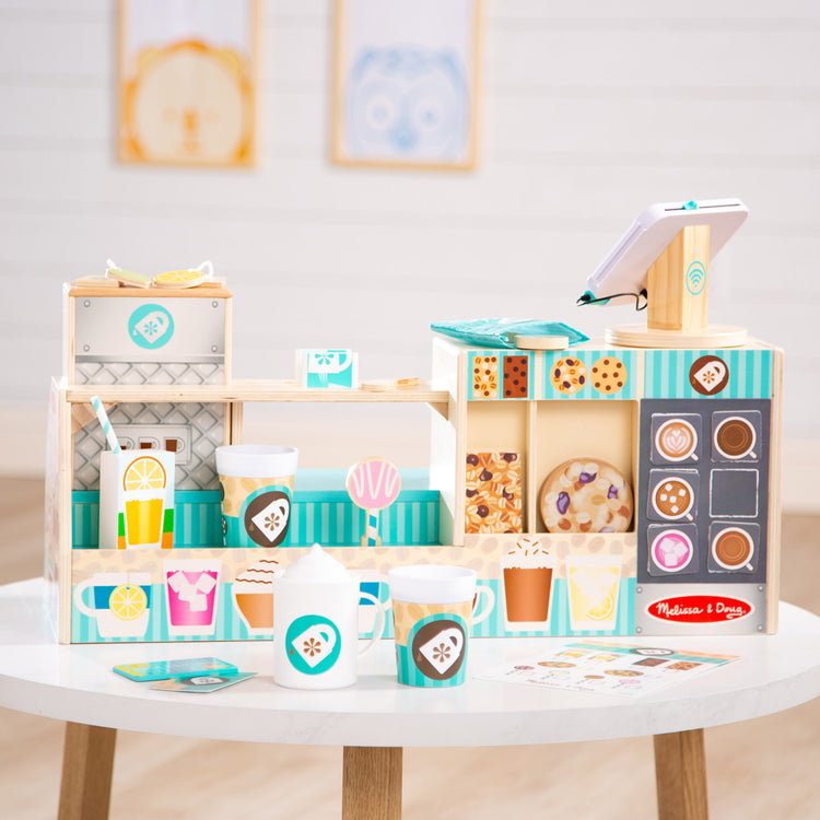 A kid playing with The Melissa & Doug Wooden Café Barista Coffee Shop (35 Pieces)