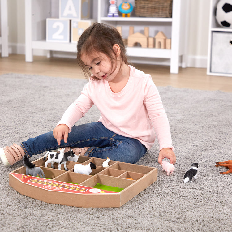 A kid playing with The Melissa & Doug Farm Friends Collectible Toy Animal Figures (10 pcs)