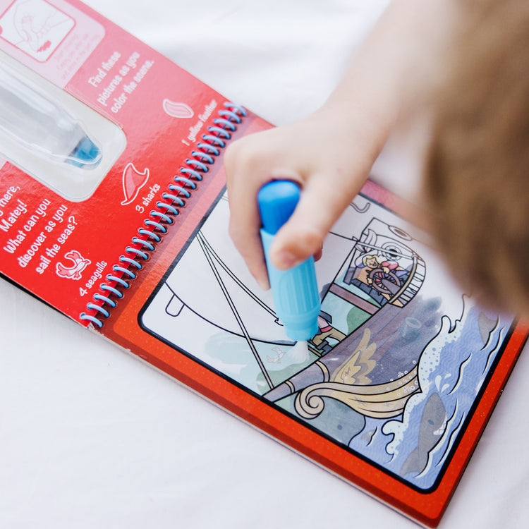 A kid playing with The Melissa & Doug On the Go Water Wow! Reusable Water-Reveal Activity Pad Travel Toy – Adventure
