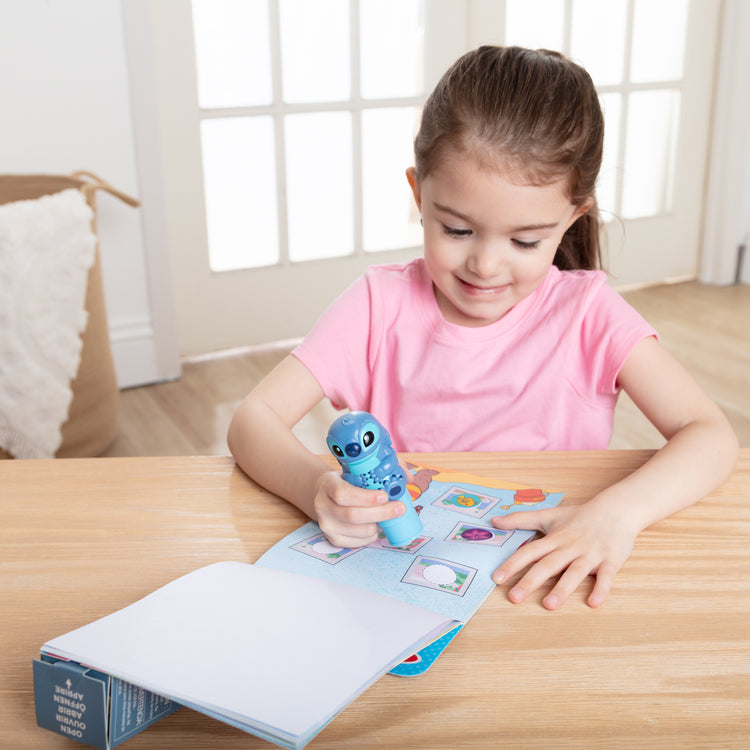 A kid playing with The Melissa & Doug Sticker WOW! Disney Stitch 24-Page Activity Pad with 300 Stickers - For Ages 3+