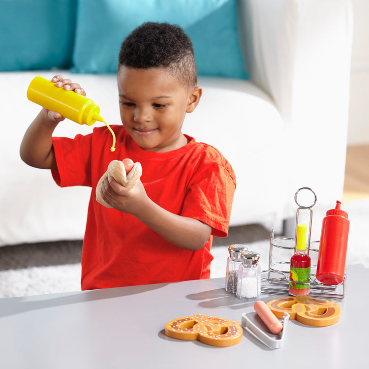 A child on white background with The Melissa & Doug Condiments Play Set (6 pcs) - Play Food, Stainless Steel Caddy