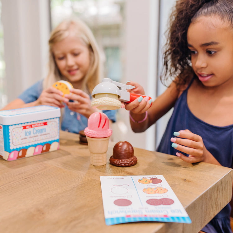 A kid playing with The Melissa & Doug Scoops and Sandwiches 13-Piece Ice Cream Play Food Set