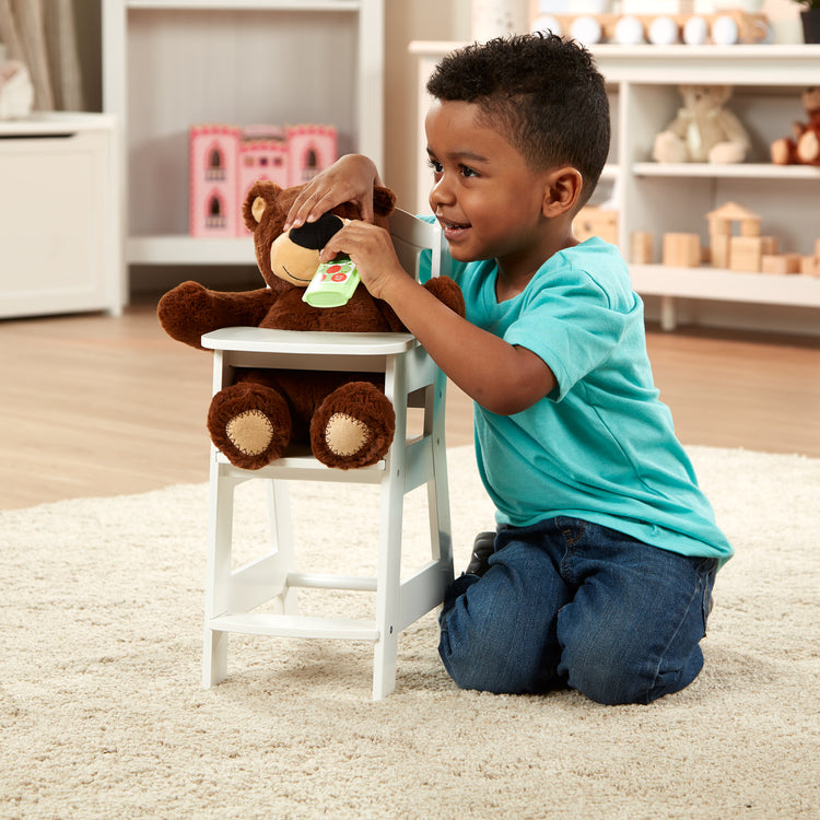 A kid playing with The Melissa & Doug Mine to Love Wooden Play High Chair for Dolls, Stuffed Animals - White (18”H x 8”W x 11”D Assembled)