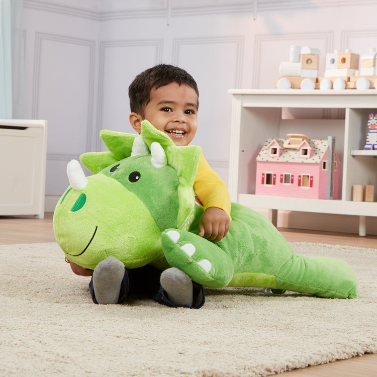 A kid playing with The Melissa & Doug Cuddle Dinosaur Jumbo Plush Stuffed Animal with Activity Card
