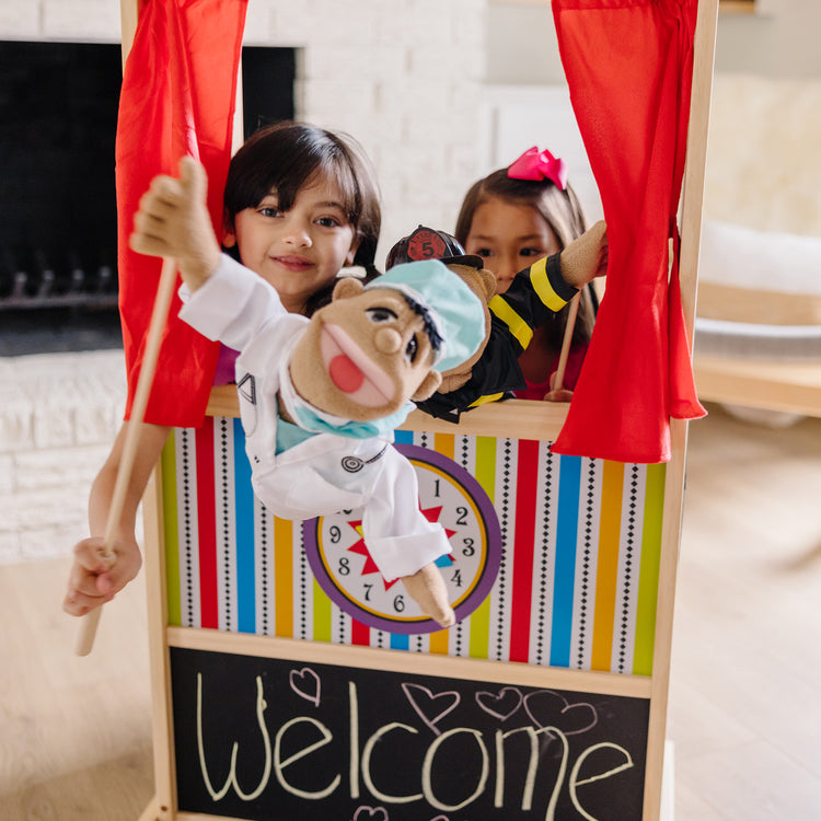 A kid playing with The Melissa & Doug Deluxe Puppet Theater - Sturdy Wooden Construction